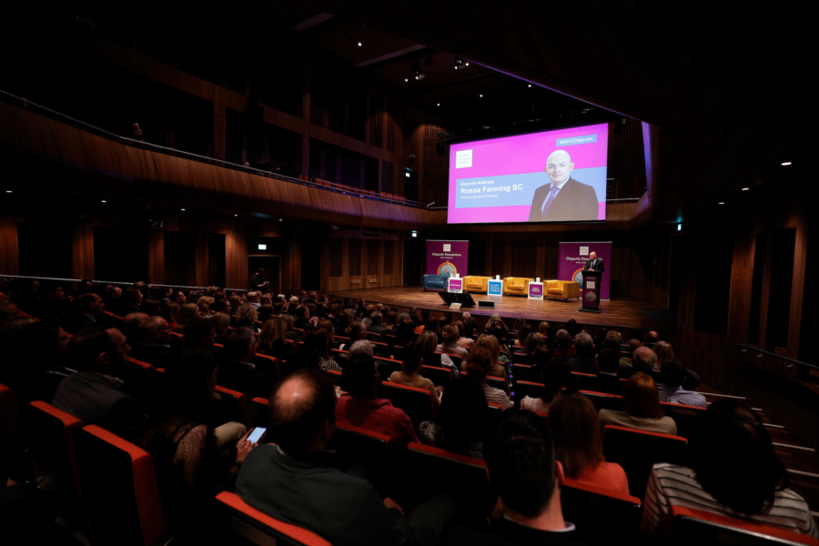 A busy conference room with a man speaking from the podium