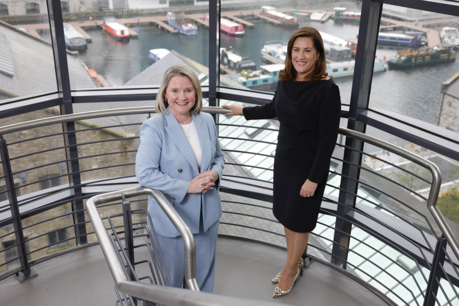 Two smiling women in business attire pictured in a stairwell with a canal in the background