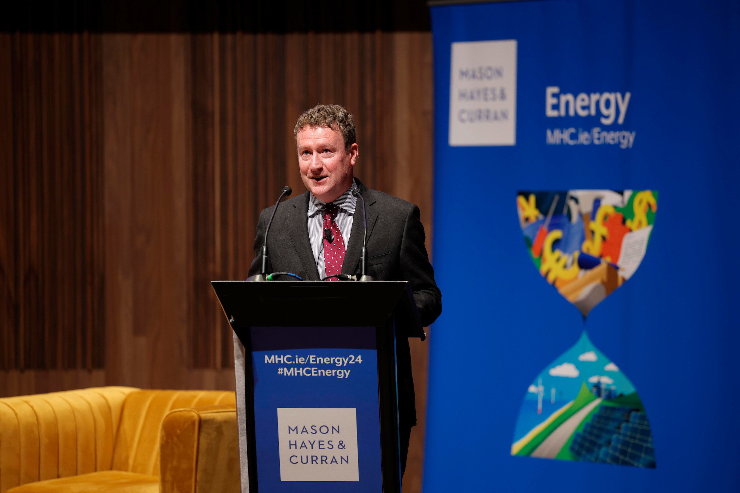 A man in business attire speaking from a podium